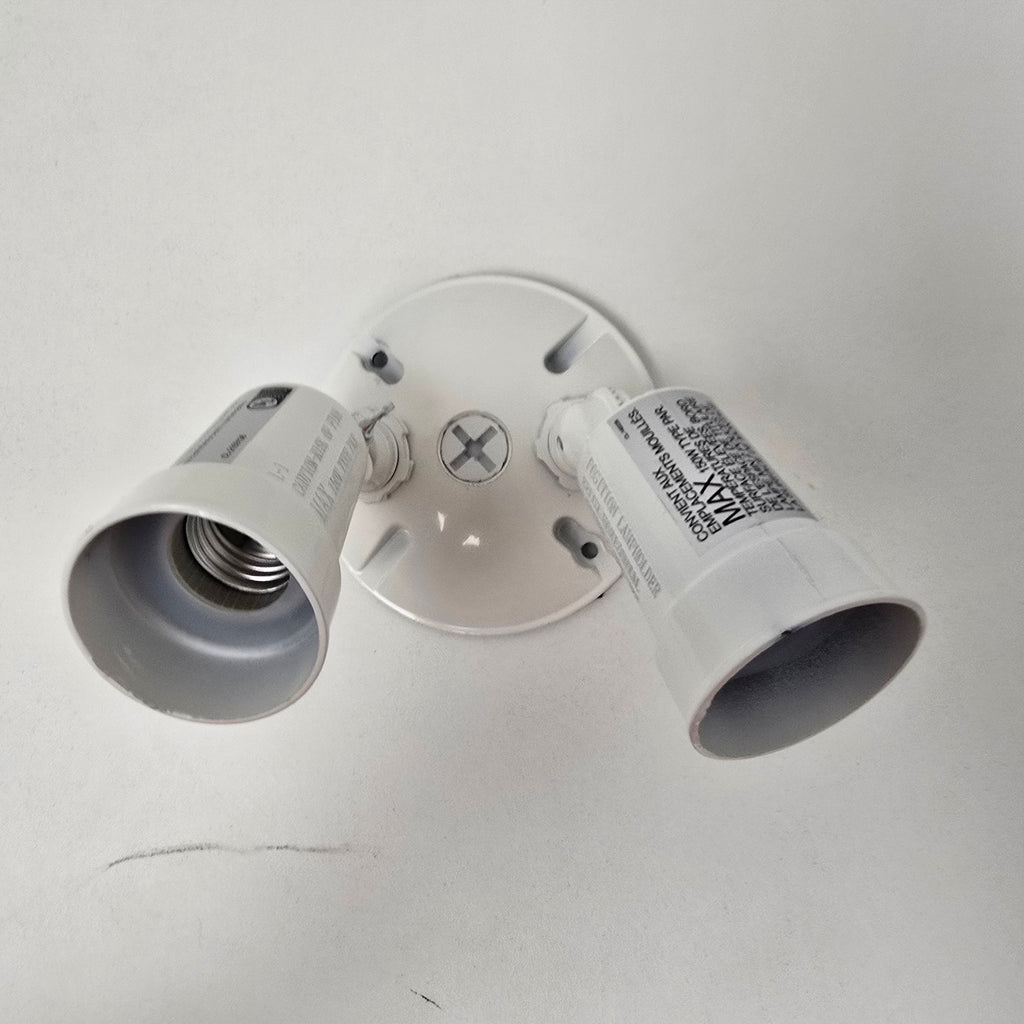 A white double-light ceiling mount fixture with two adjustable light sockets, shown against a plain white ceiling.